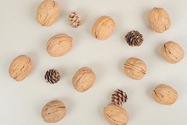 Noix et pommes de pin éparpillées sur une surface beige