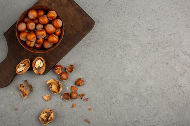 Noix une vue de dessus des noisettes et des noix entières et décortiquées sur un bureau en bois et un sol gris