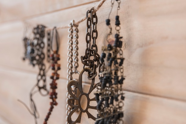 De nombreux bracelets métalliques suspendus à une ficelle contre un mur en bois