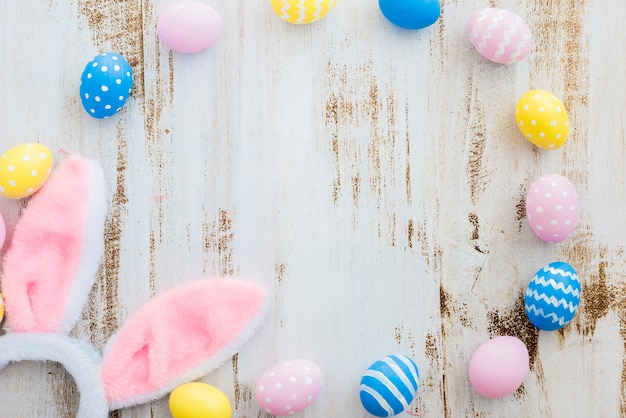 De nombreux œufs de Pâques avec des oreilles de lapin sur une table en bois