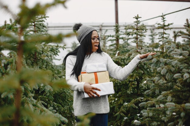 Notion d'hiver. Femme dans un pull gris. Vendeuse d'arbre de Noël.