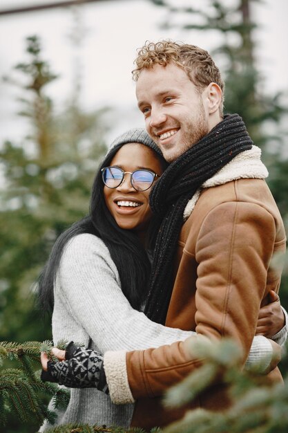 Notion d'hiver. Mec en manteau marron. Vendeur d'arbre de Noël. Couple international.