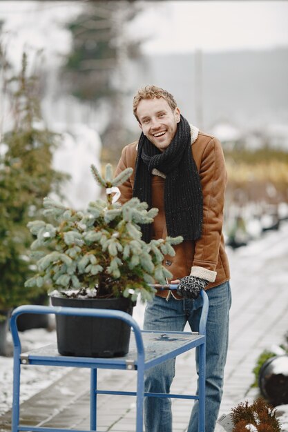 Notion d'hiver. Mec en manteau marron. Vendeur d'arbre de Noël.