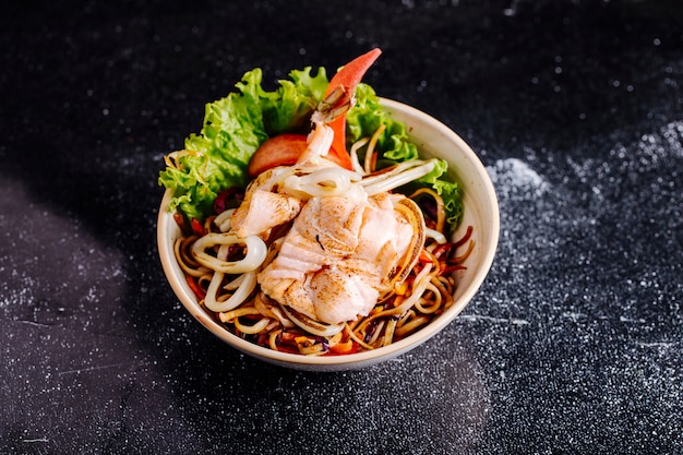 Nouilles chinoises avec filet de poisson, tomates et laitue dans le bol.