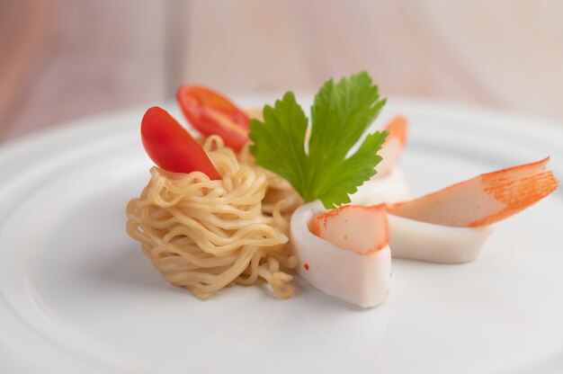 Nouilles instantanées sautées aux crevettes et au crabe dans un plat blanc.