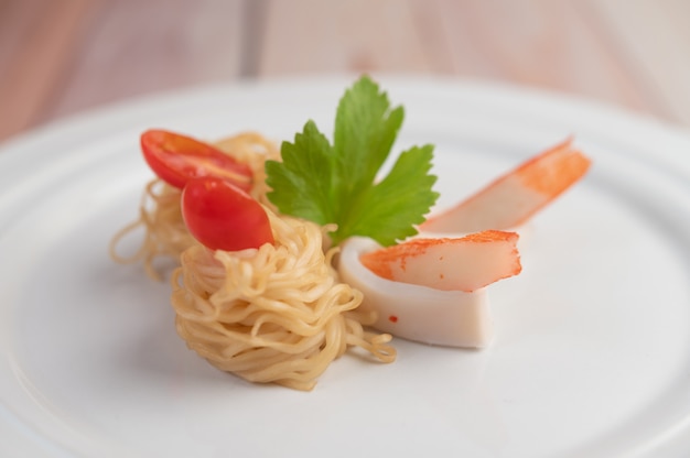 Nouilles instantanées sautées aux crevettes et au crabe dans un plat blanc.