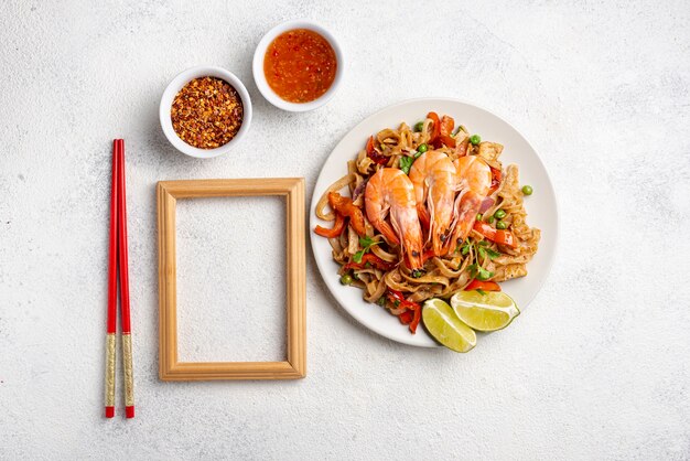 Nouilles plats poser avec des baguettes de légumes et de crevettes et des épices avec cadre en bois