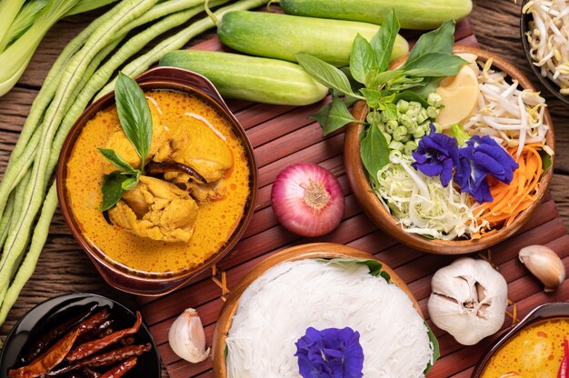 Nouilles de riz dans un bol de pâte de curry avec piment, concombre, haricot long, citron vert, ail et oignon nouveau