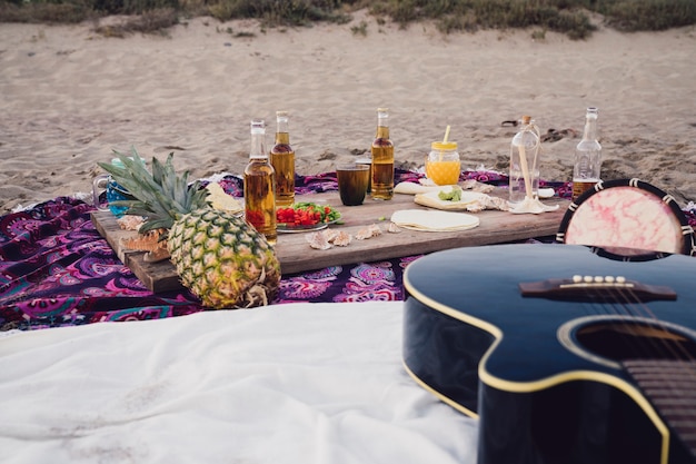 Photo gratuite nourriture, boissons et guitare à la plage