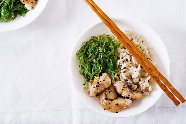 Nourriture japonaise. Bol de riz, poisson blanc bouilli et salade de wakame chuka ou d'algues. Vue de dessus. Mise à plat
