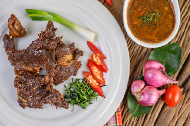 Nourriture thaïe au boeuf frit sur une plaque blanche avec oignon de printemps, feuilles de lime kaffir, piments, oignons rouges et tomates.