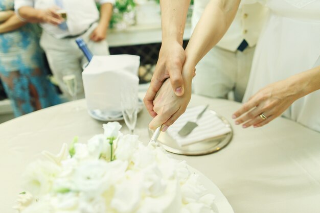 Les nouveaux mariés coupent le gâteau de mariage décoré avec des seastars argentés