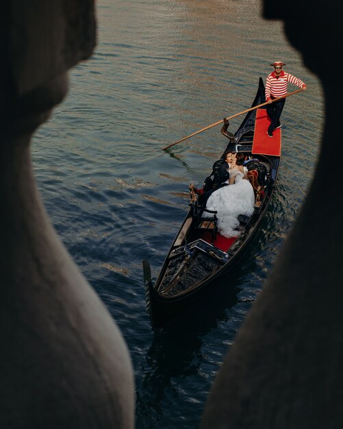 Les nouveaux mariés s'embrassant sur la gondole de luxe lors d'une promenade sur le canal