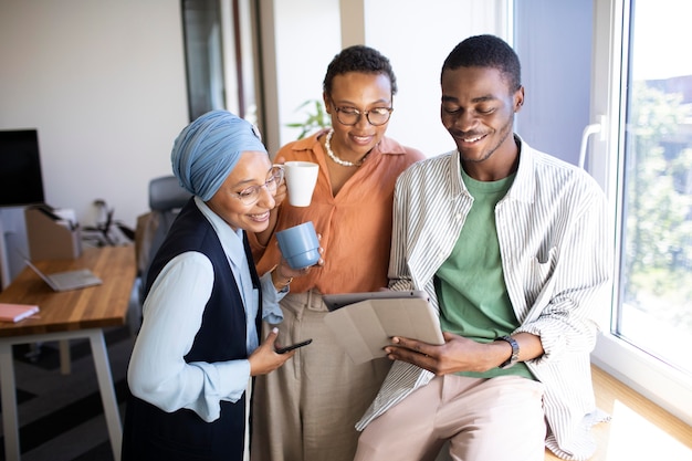 Photo gratuite nouvel employé masculin conversant avec des collègues féminines à son nouveau travail de bureau