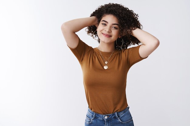 Nouvelle coupe de cheveux fraîche et confiante. Jolie fille métisse joyeuse jouant des cheveux noirs bouclés souriant satisfait se sentir détendu satisfait heureux a obtenu une coiffure géniale debout sur fond blanc