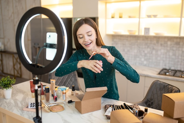 Nouvelle qualité. Jeune femme appliquant un échantillon de nouvelle crème tonifiante sur sa main