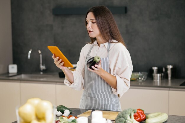 Nouvelles idées. Jeune femme au foyer à la recherche de nouvelles idées de cuisine sur internet