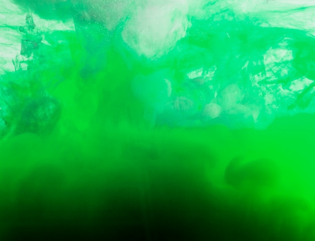 Nuage vert vif de brume dans un liquide