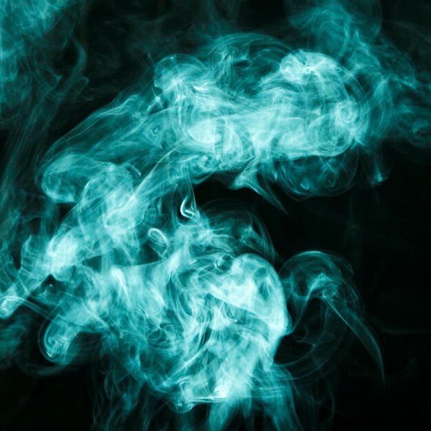 Des nuages de fumée turquoise étalés sur un fond noir