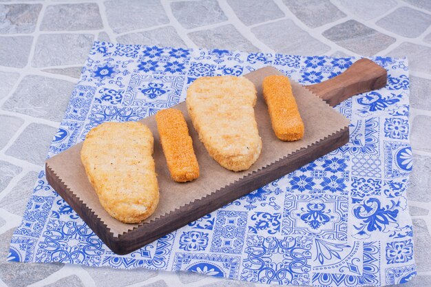Nuggets de poisson isolés sur une planche de bois.