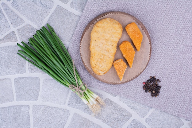 Nuggets de poisson sur un plateau en bois avec des oignons verts.