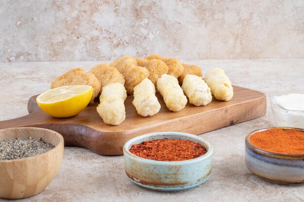 Nuggets de poulet et bâtonnets de fromage avec des épices à part.