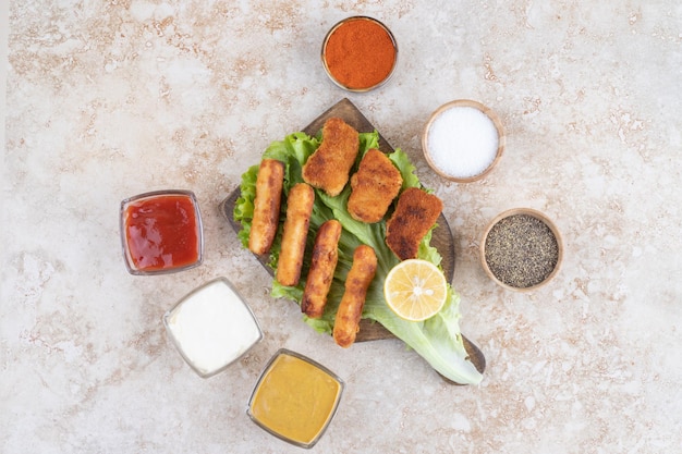 Nuggets de poulet et saucisses frites sur une feuille de laitue verte sur une planche en bois.