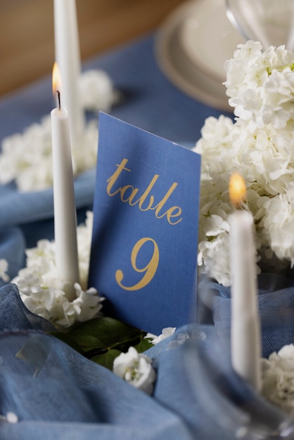Photo gratuite numéro de table de mariage à angle élevé avec des bougies allumées