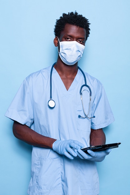 Nurse holding tablet tout en regardant la caméra sur fond isolé