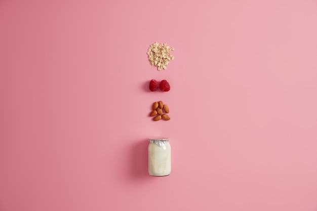 Nutrition biologique, concept de petit-déjeuner sain. Yaourt ou lait végétalien en pot, céréales d'avoine, framboise et amande pour faire de savoureuses collations. Ingrédients naturels. Repas végétarien et régime