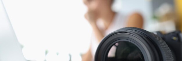 Objectif de l'appareil photo sur fond de femme travaillant sur ordinateur travaillant comme photographe et journaliste