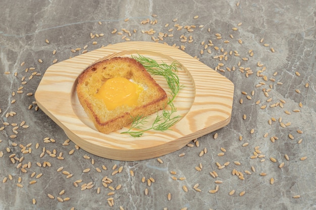 Oeuf au plat à l'intérieur d'une tranche de pain grillé sur une plaque en bois. Photo de haute qualité