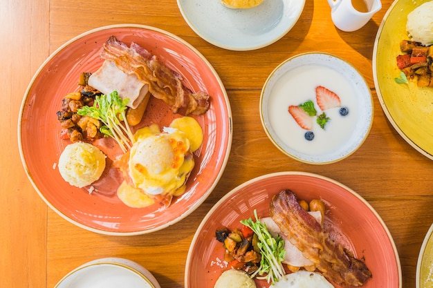 Photo gratuite oeuf au plat avec oeufs bénédictine et omelette autour de la saucisse de jambon bacaon en plaque