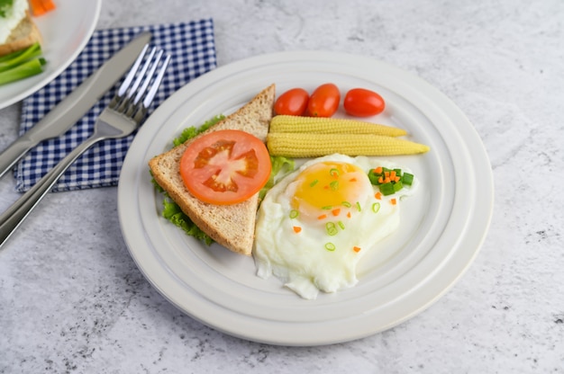 Un œuf au plat portant sur un toast, garni de graines de poivre avec des carottes, du petit maïs et des oignons de printemps.