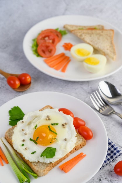 Un œuf au plat portant sur un toast, garni de graines de poivre avec des carottes, du petit maïs et des oignons de printemps.