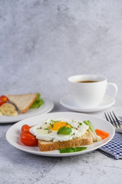 Un œuf au plat portant sur un toast, garni de graines de poivre avec des carottes et des oignons de printemps.