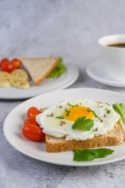 Un œuf au plat portant sur un toast, garni de graines de poivre avec des carottes et des oignons de printemps.