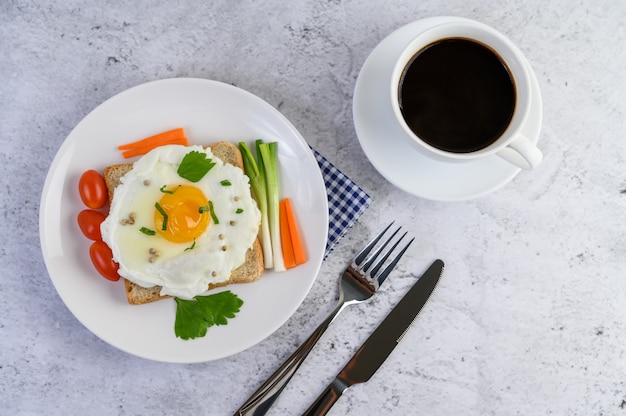 Un œuf au plat portant sur un toast, garni de graines de poivre avec des carottes et des oignons de printemps.