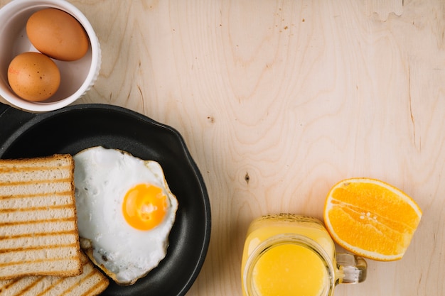 Oeuf au plat avec des toasts et du jus