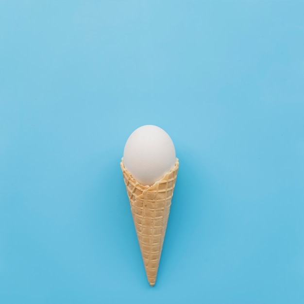 Oeuf blanc en corne de gaufre sur fond bleu