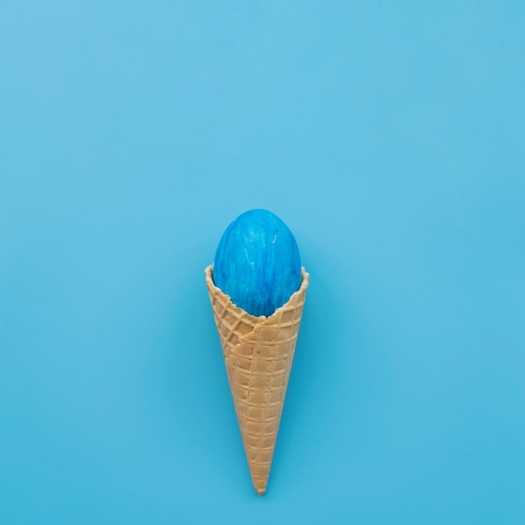 Photo gratuit oeuf bleu en cône de gaufre sur fond bleu