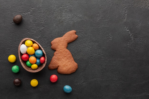 Oeuf de Pâques au chocolat rempli de bonbons colorés et de biscuits en forme de lapin