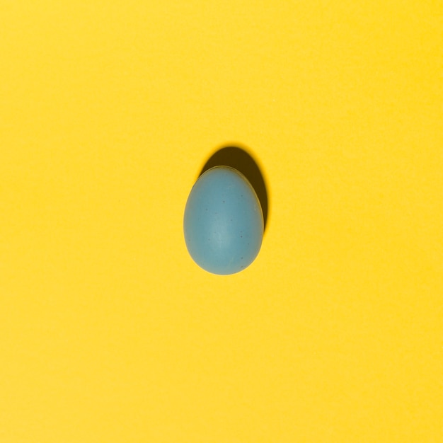 Oeuf de Pâques bleu sur une table jaune