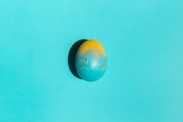 Photo gratuite oeuf de pâques coloré sur la table bleue