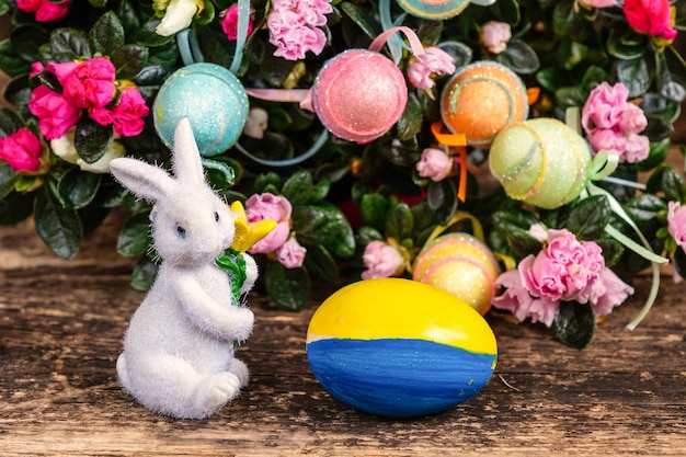Oeuf de Pâques décoré aux couleurs ukrainiennes au premier plan du lapin de Pâques et des fleurs