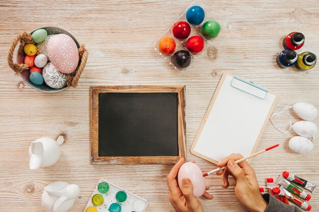 Oeuf de peinture à la main à table avec tableau noir