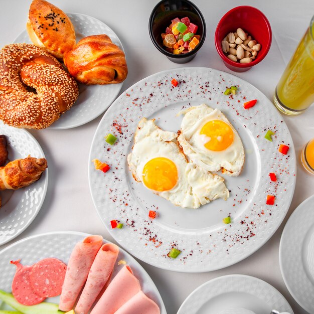 Oeufs au plat dans une assiette avec d'autres repas vue de dessus sur fond blanc