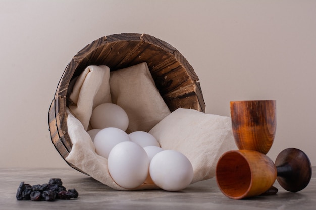 Oeufs blancs dans un seau en bois.