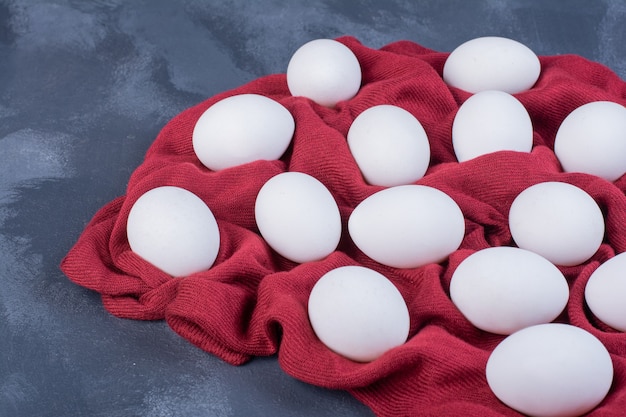 Oeufs blancs isolés sur un morceau de nappe rouge