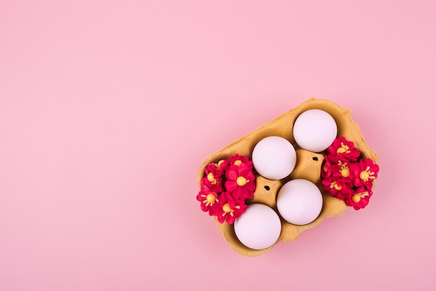 Photo gratuite oeufs blancs en rack avec des fleurs